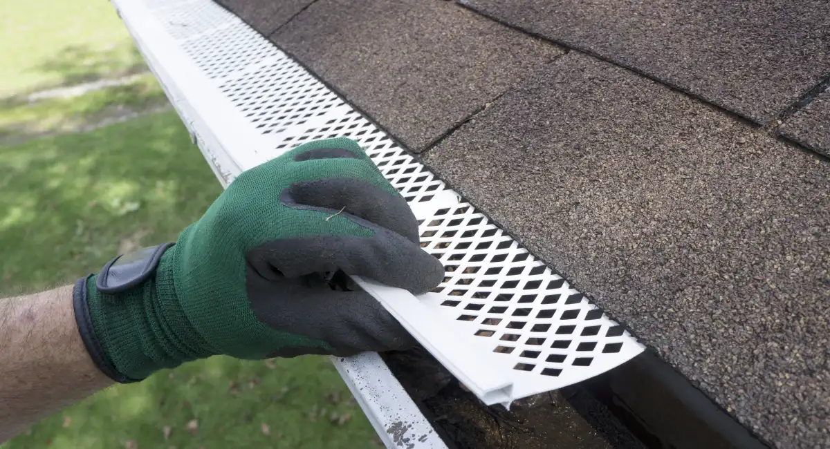 A technician installing gutter protection against rodents