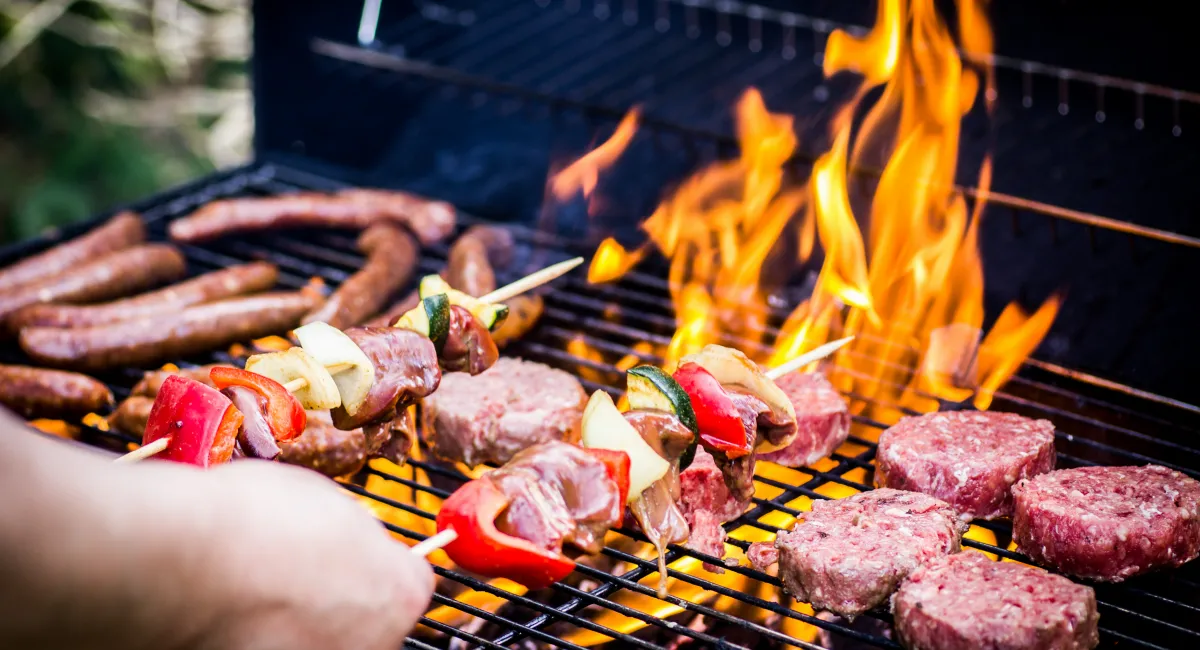 kebabs, burgers and sausages on an active outdoor bbq