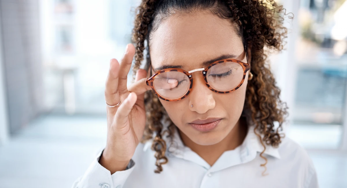 woman with glasses rubbing eyes