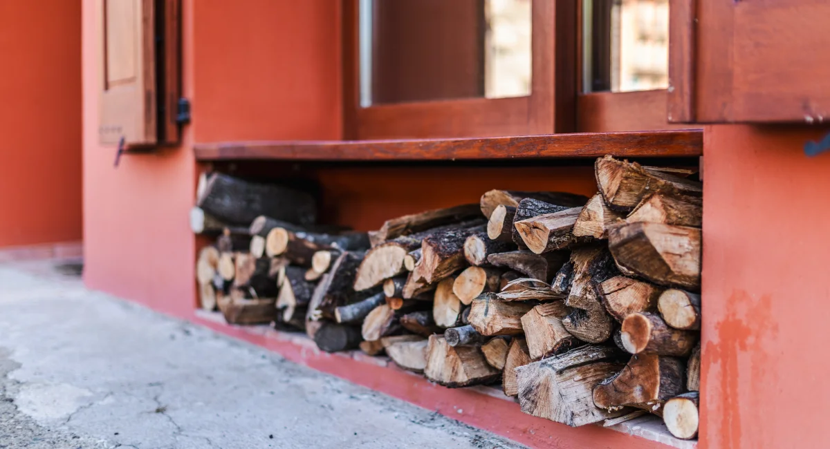 Stacked firewood beneath a wooden window