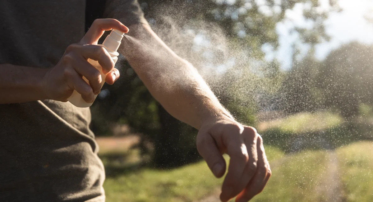 A man spraying insect repellent on his arm