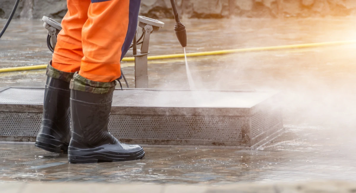 Washing the fountain under a powerful jet of water pressure, a worker in rubber boots