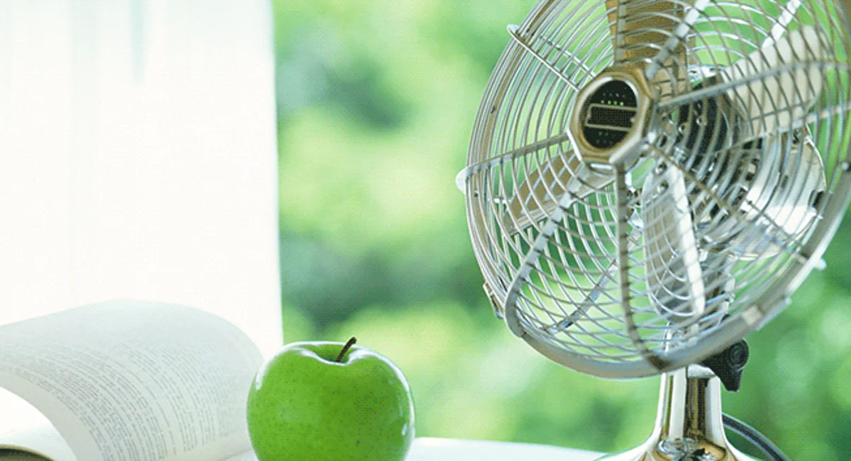 Oscillating fan in front of book and apple 