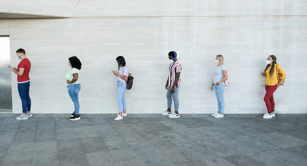 people socially distancing standing apart from each other in queue
